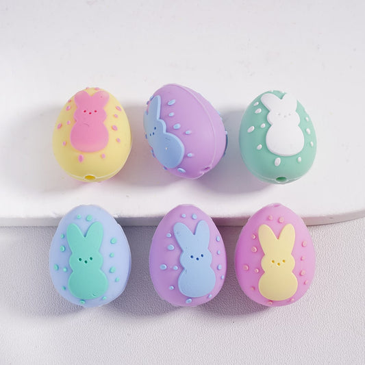 Set of pastel-colored Easter egg-shaped toys with bunny designs on a white background
