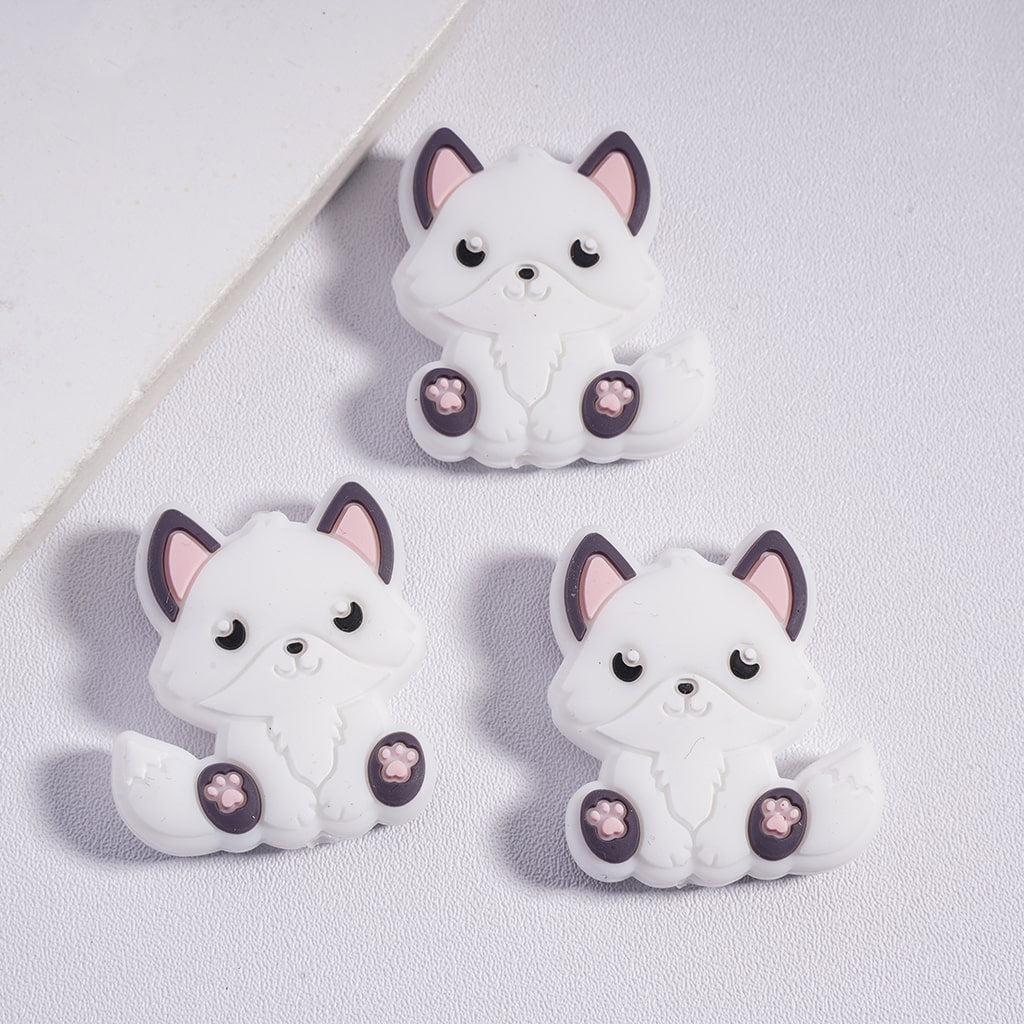 Three white cat-shaped figurines with pink paws on a light gray background