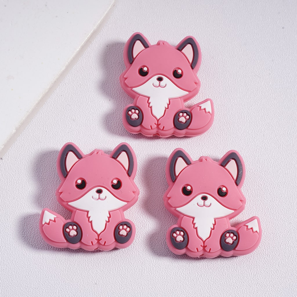 Three pink cartoon fox figurines on a light gray background