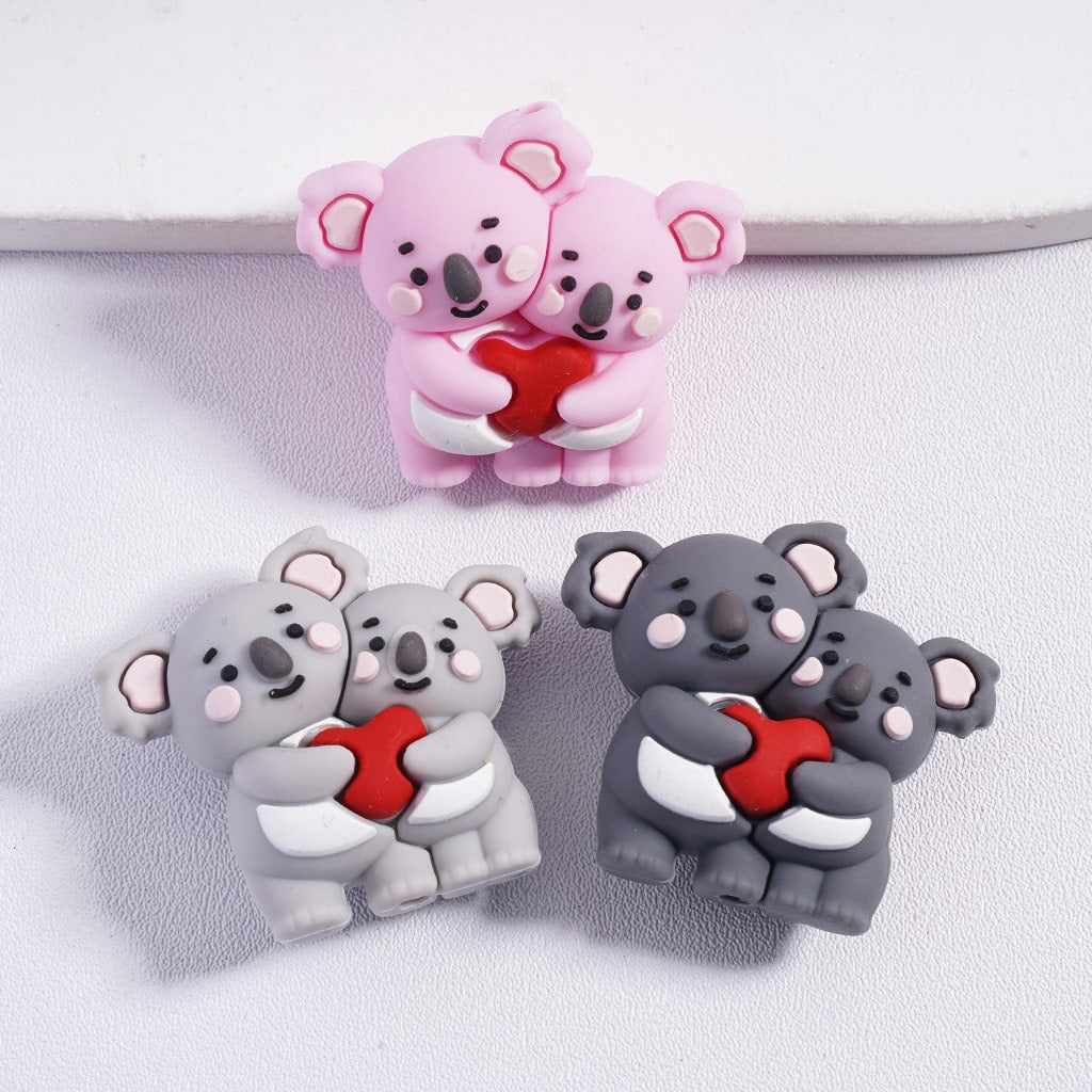 Two pairs of koala-shaped earrings in pink and gray on a white background.
