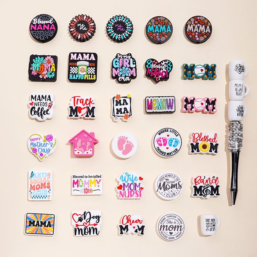 An assortment of silicone beads with various designs related to mothers and motherhood, displayed on a neutral background.

