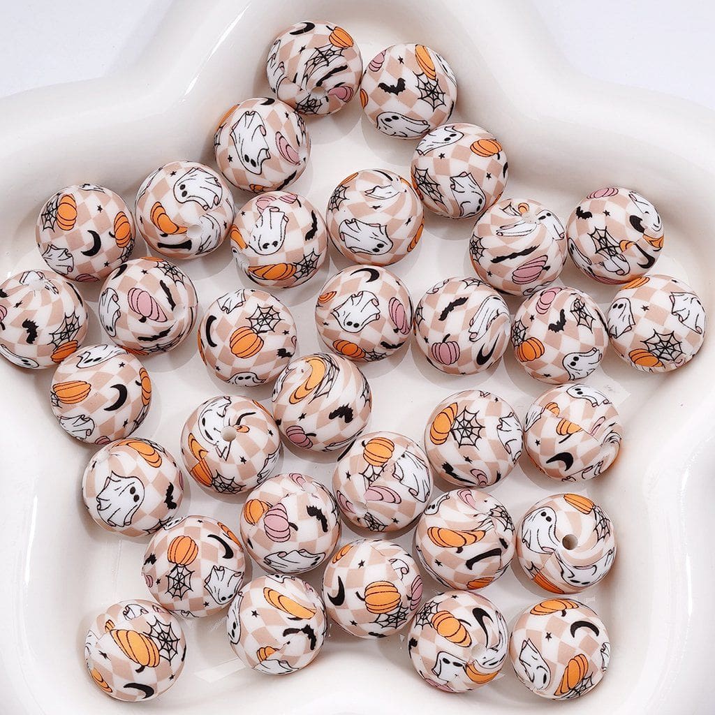 Decorative beads with Halloween-themed designs on a white surface

