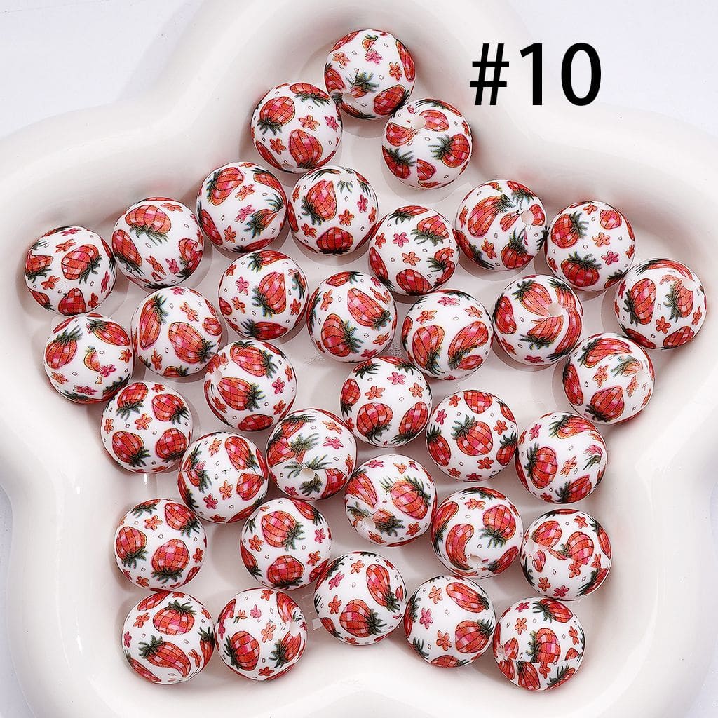 White spherical beads with red strawberry pattern on a white background

