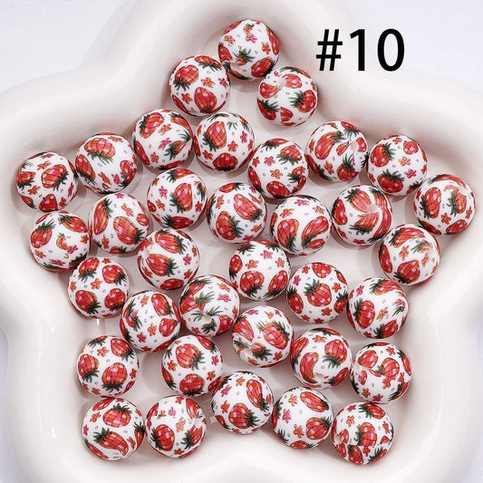 White spherical beads with red strawberry pattern on a white background

