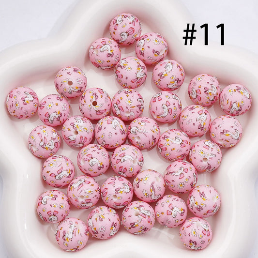 Pink beads with unicorn designs on a white surface

