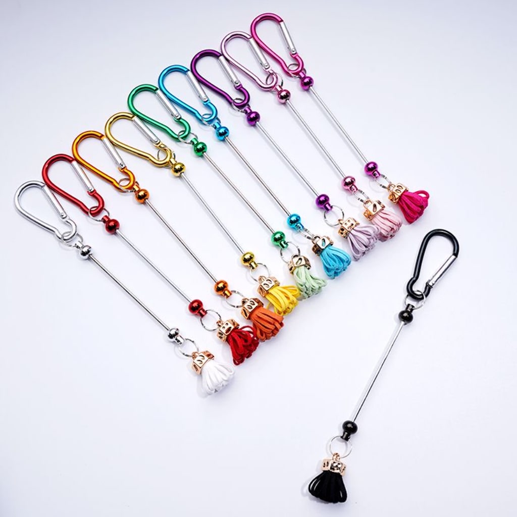 A collection of colorful metal carabiner hooks with beadable tassels in various colors.

