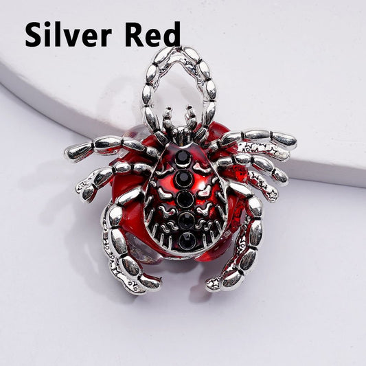 Silver and red spider-shaped pendant on a white background

