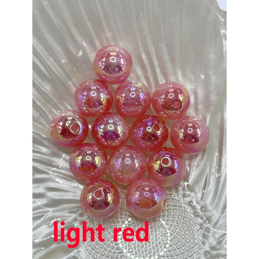 A collection of colorful glossy acrylic beads with glitter inside, displayed on a white surface, alongside a beadable pen with a similar glossy finish.

