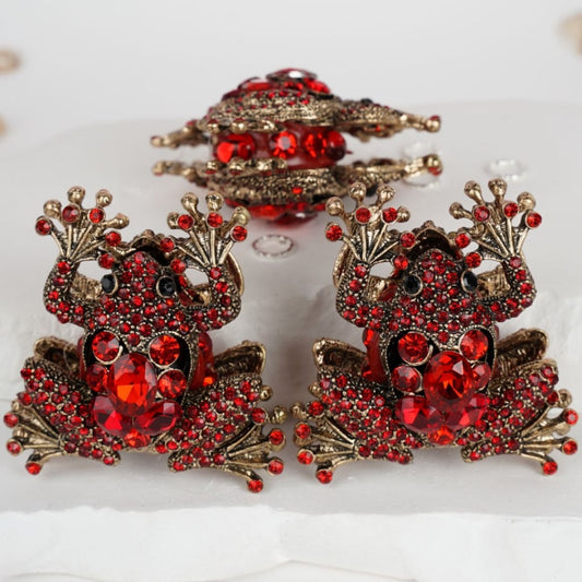 A set of gold frog-shaped clay beads with sparkling green rhinestones.

