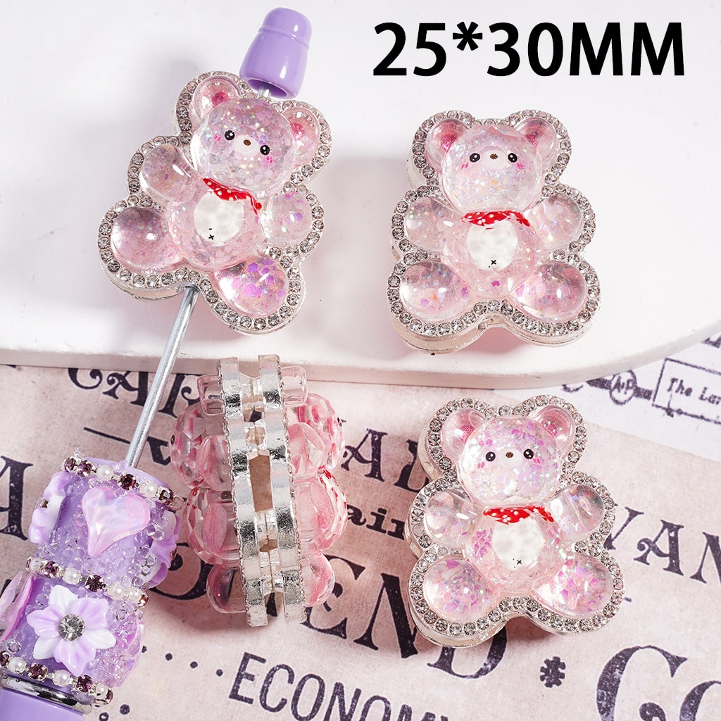 Decorative bear-shaped pins with rhinestones on a surface with text.

