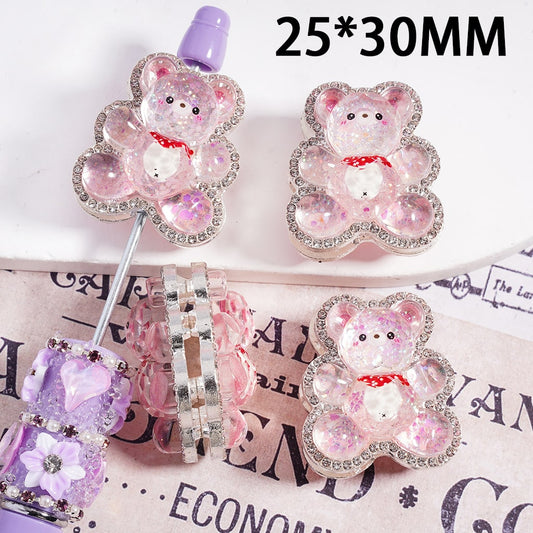 Decorative bear-shaped pins with rhinestones on a surface with text.

