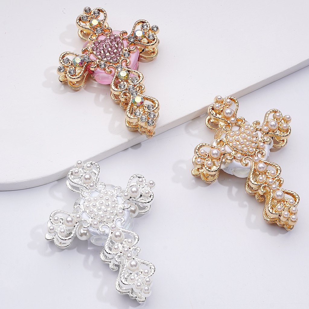 Three decorative crosses, two gold and one silver, on a white surface.

