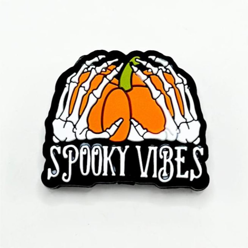 A silicone focal bead featuring a design of skeleton hands holding a pumpkin with the text 'SPOKY VIBES' below.

