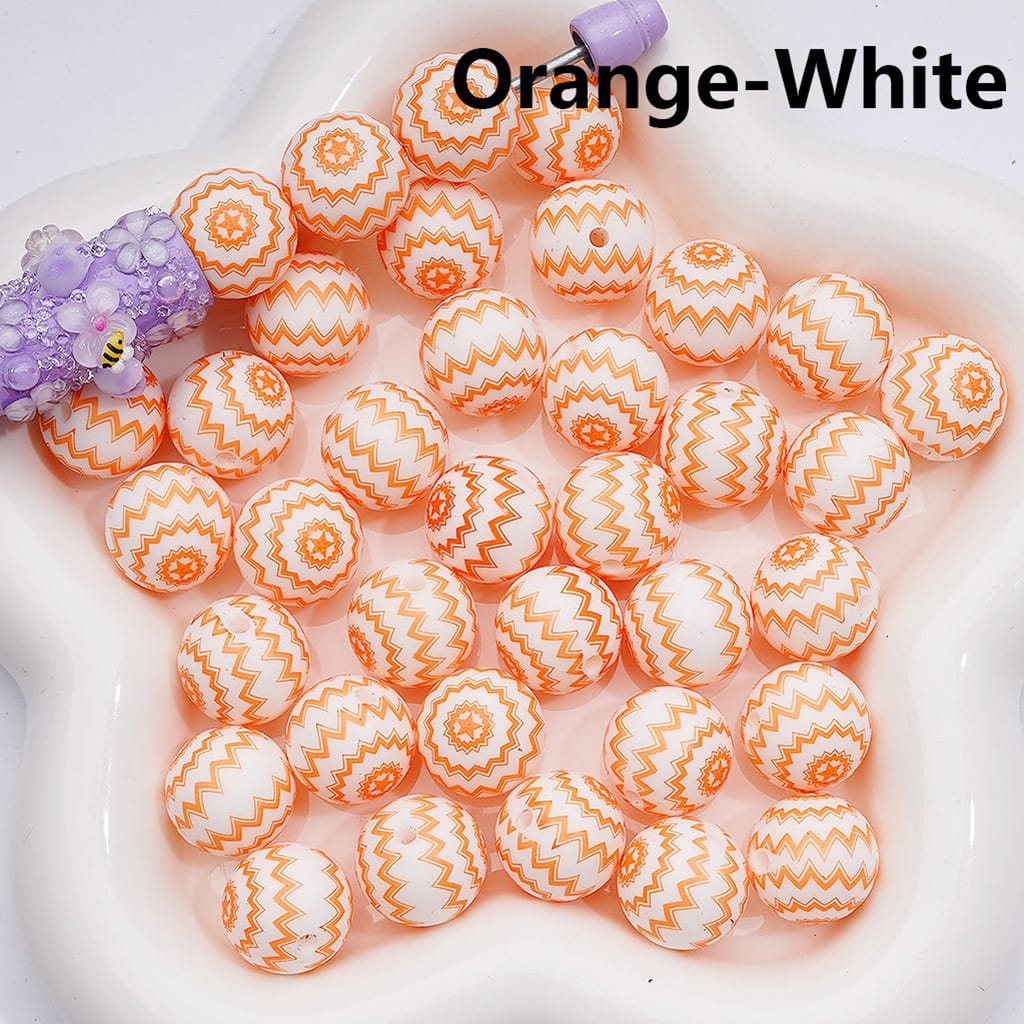 Orange and white patterned beads on a white plate with a purple toy.

