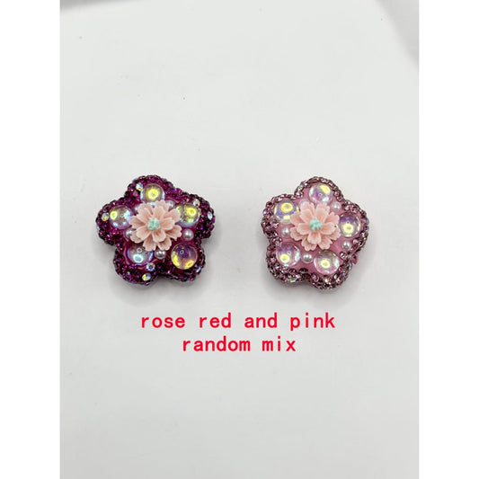 A collection of flower-shaped clay beads with clear rhinestones and solid colors, displayed alongside a beadalon tool.

