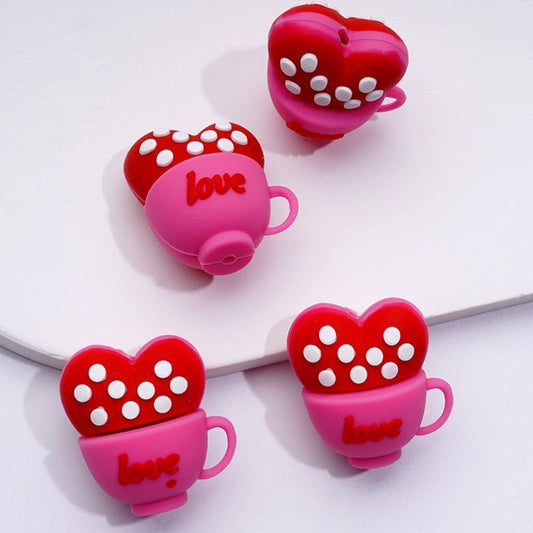 A collection of colorful silicone beads shaped like red hearts with the word 'love' and white spots inside them.

