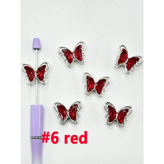 A collection of silver alloy metal beads designed in the shape of butterflies, adorned with rhinestones and acrylic beads.

