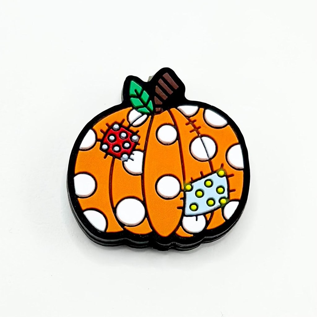 A silicone bead featuring a big pumpkin with white dots and patches design, commonly associated with Halloween.

