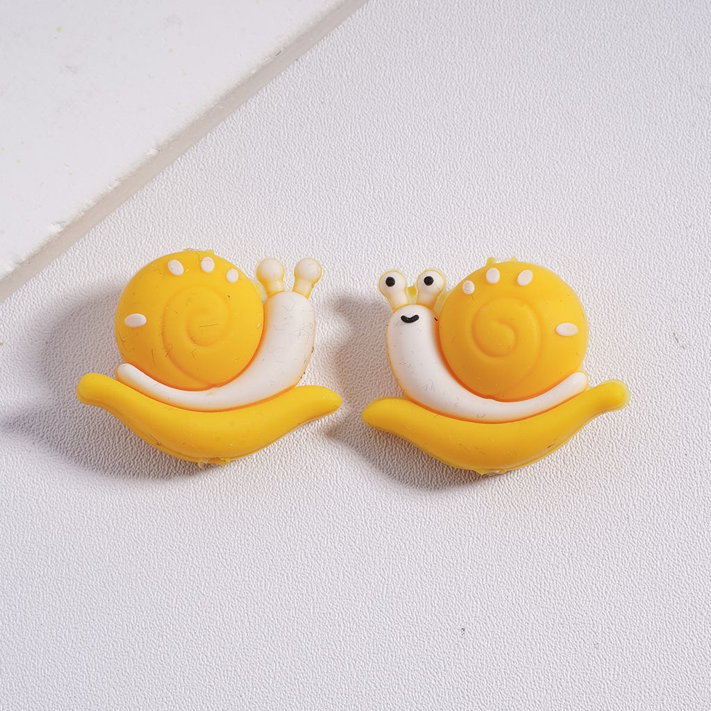 A collection of colorful silicone beads shaped like snails, with two in green and two in orange.

