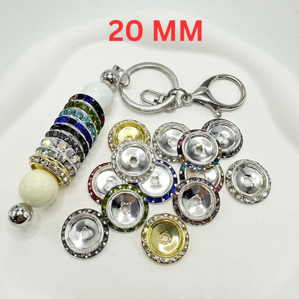 A collection of round rhinestone spacers in various solid colors, 20mm in size, displayed alongside a keychain.


