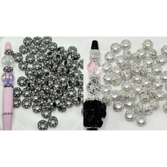 A collection of metal beadable spacers with AB color rhinestones, alongside a bead pen, displayed on a white surface.

