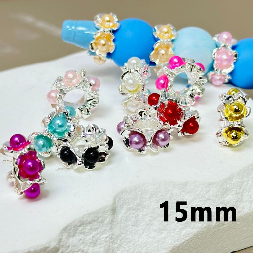A collection of silver metal alloy flower spacers with colorful pearls inside, displayed on a surface.

