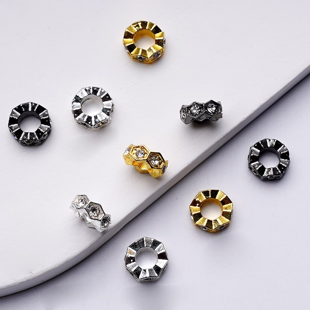 Set of round metallic earrings in gold, silver, and black on a white surface.

