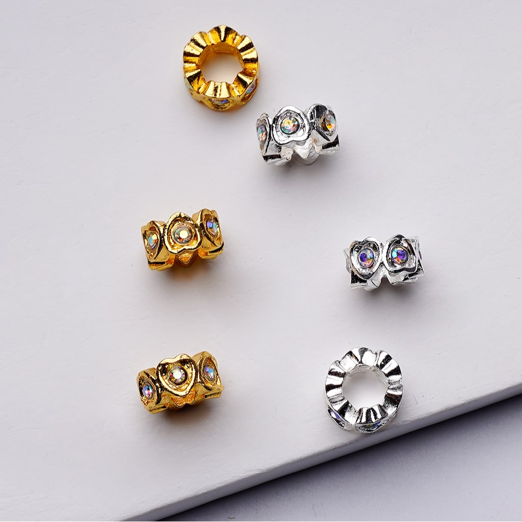 Gold and silver jewelry pieces with gemstones on a light gray background

