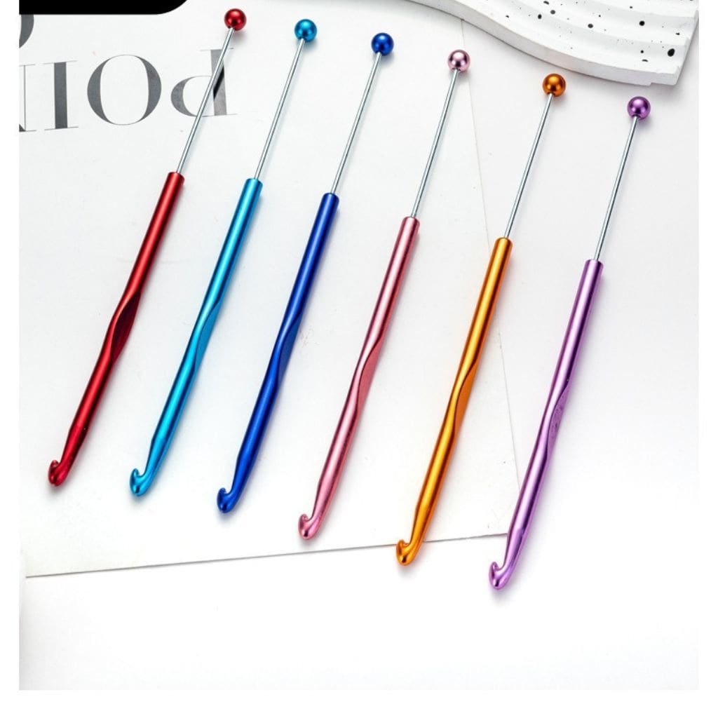 A selection of beadable metal crochet needles in various colors including red, blue, orange, purple, and silver, with colorful handles.

