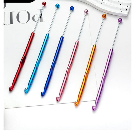 A selection of beadable metal crochet needles in various colors including red, blue, orange, purple, and silver, with colorful handles.

