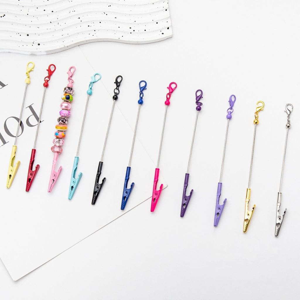 A selection of colorful metal keychains with crocodile clips and mini lobster clasps arranged neatly on a surface.

