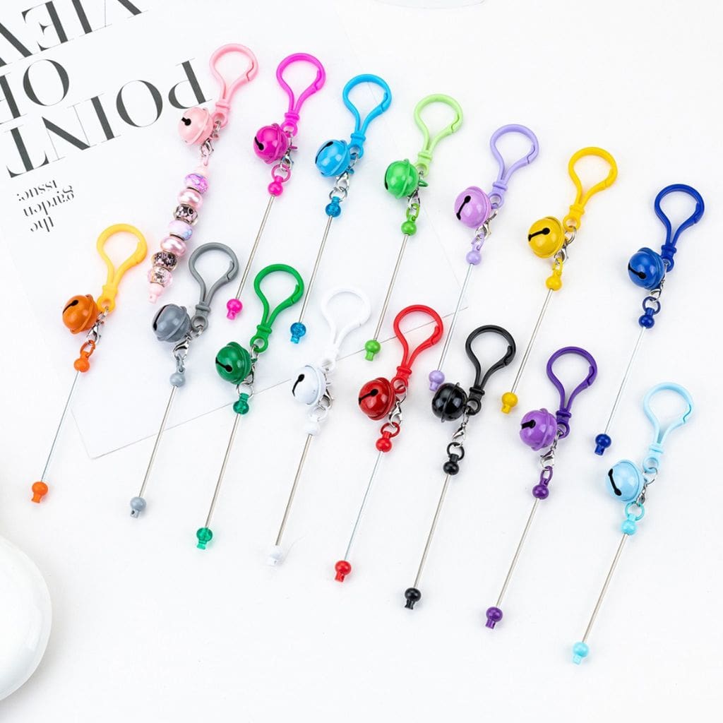 A variety of colorful beadable DIY keychains with bar carabiner hooks and bells.

