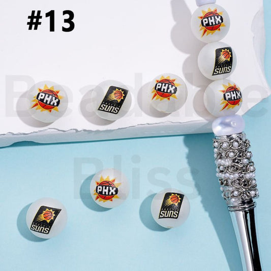 White balls with Phoenix Suns logo and a decorative pen on a light blue background

