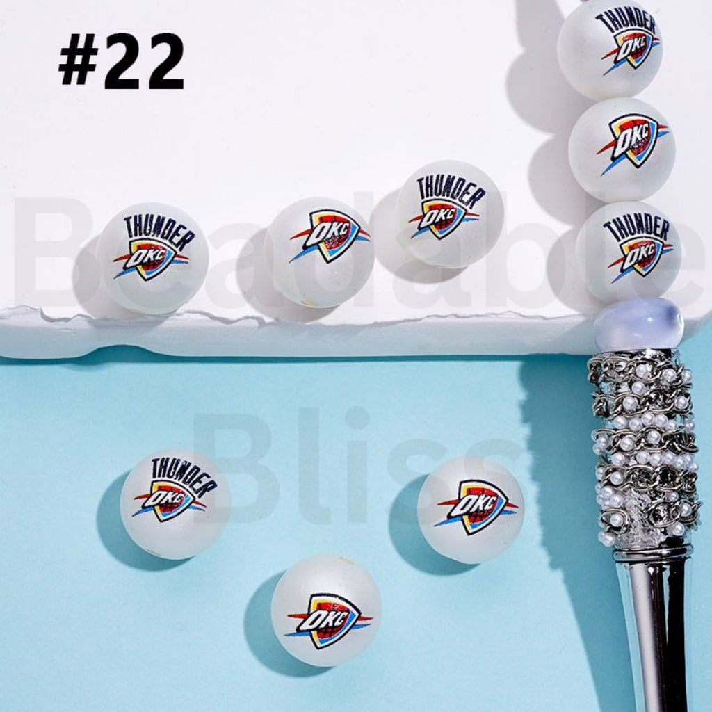 Oklahoma City Thunder branded ping pong balls on a blue surface with a decorative pen.

