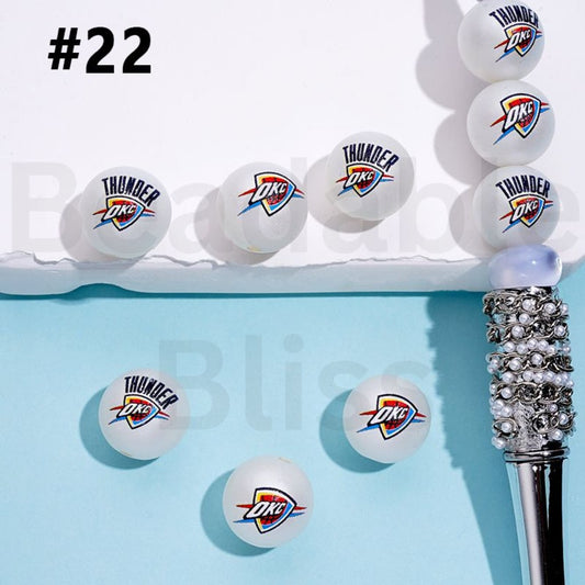 Oklahoma City Thunder branded ping pong balls on a blue surface with a decorative pen.


