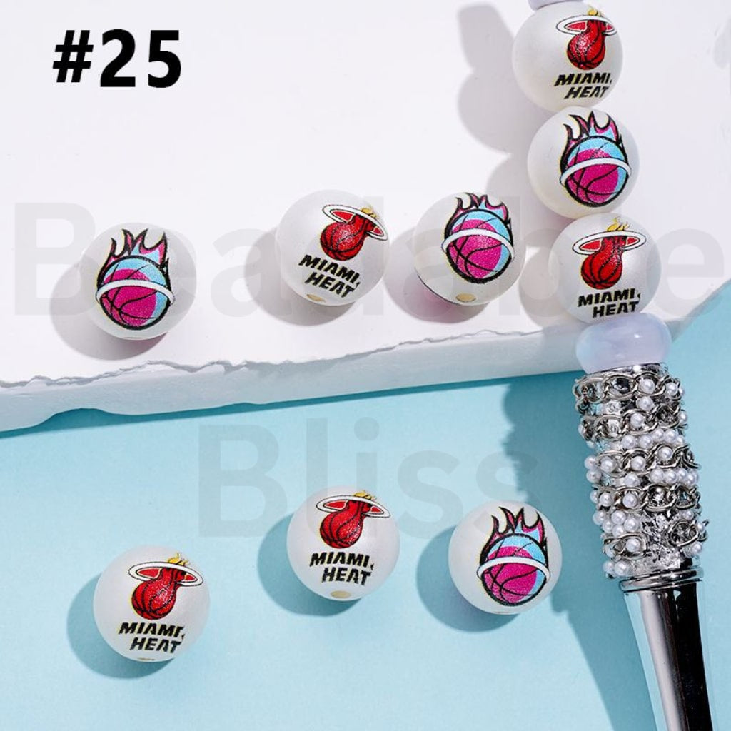 Miami Heat-themed earrings on a stand with a decorative pen on a light blue background.

