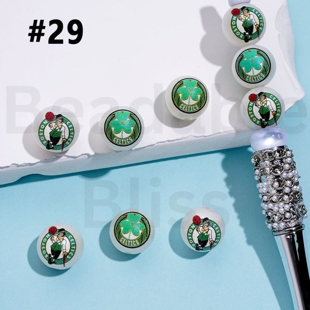 Set of Boston Celtics-themed lip glosses on a light blue background

