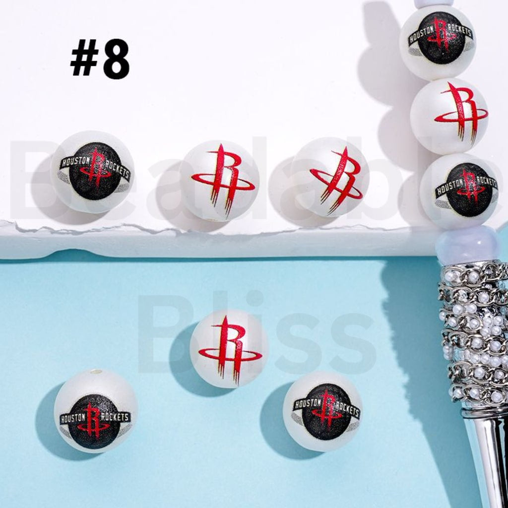 Houston Rockets-themed ping pong balls on a blue background with a decorative pen.

