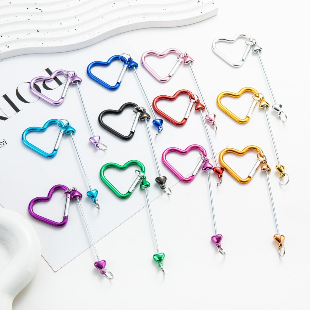 A collection of colorful metal keychains shaped like hearts with bars in the center, displayed on a white surface.

