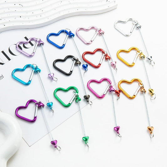 A collection of colorful metal keychains shaped like hearts with bars in the center, displayed on a white surface.

