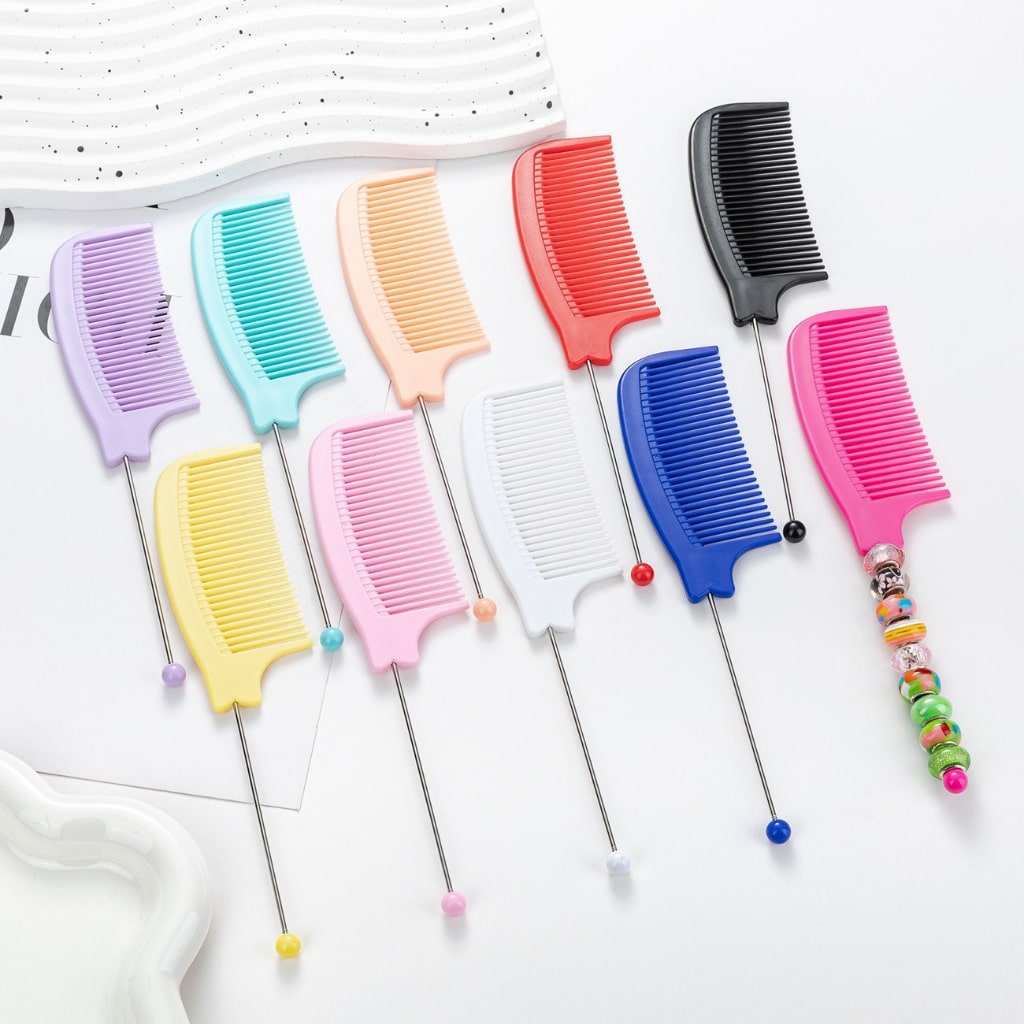 A collection of colorful pointed-tail combs laid out on a surface, with each comb featuring a different solid color and a decorative bead on the end.

