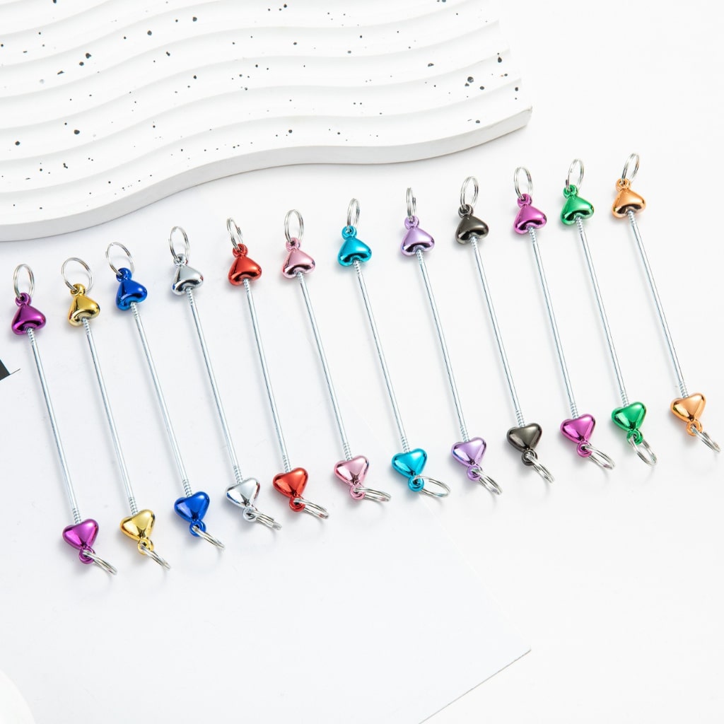A collection of metallic color keychain bars with heart designs, displayed in a row on a light background.

