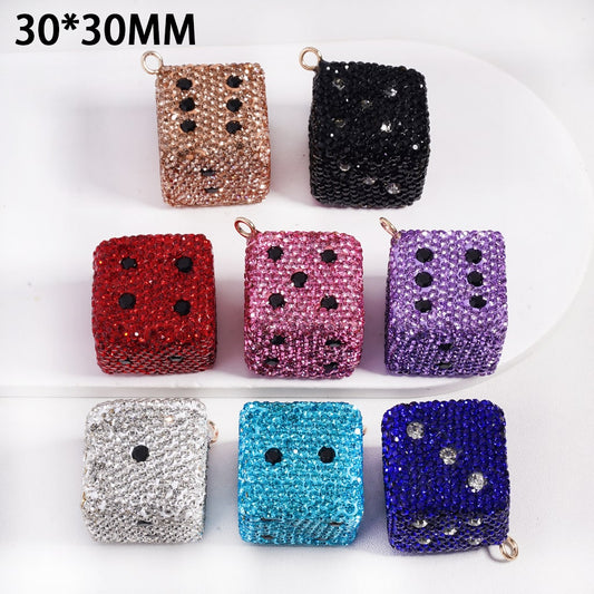 Set of glittery dice-shaped containers in various colors on a white background

