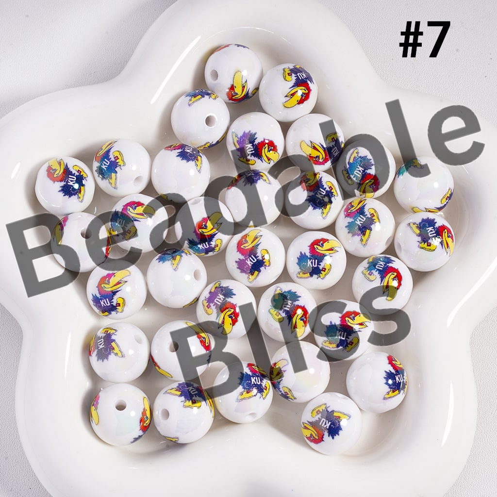 White beads with colorful KU Jayhawks logos on a white plate, labeled 'Beadable Beads'.


