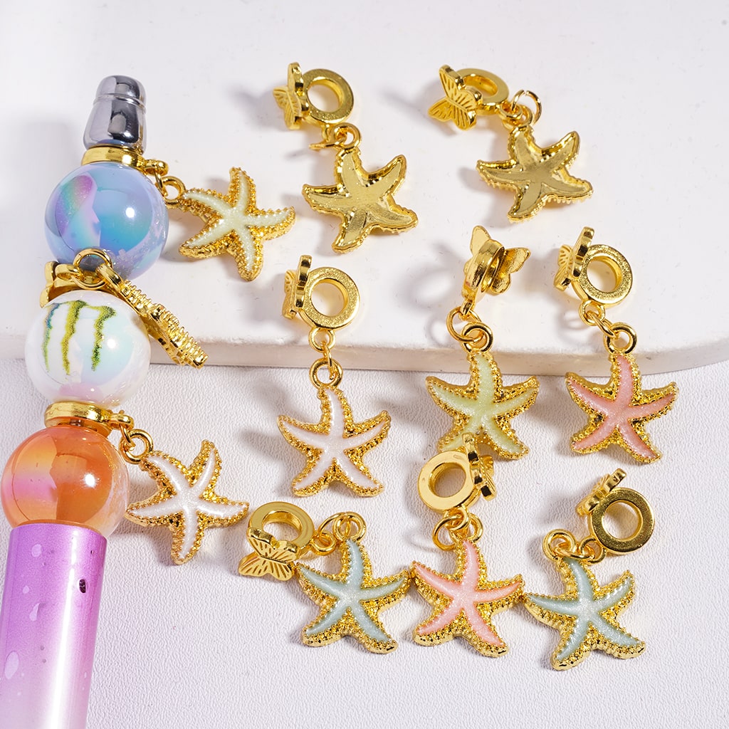 Gold starfish and butterfly charms on a white background