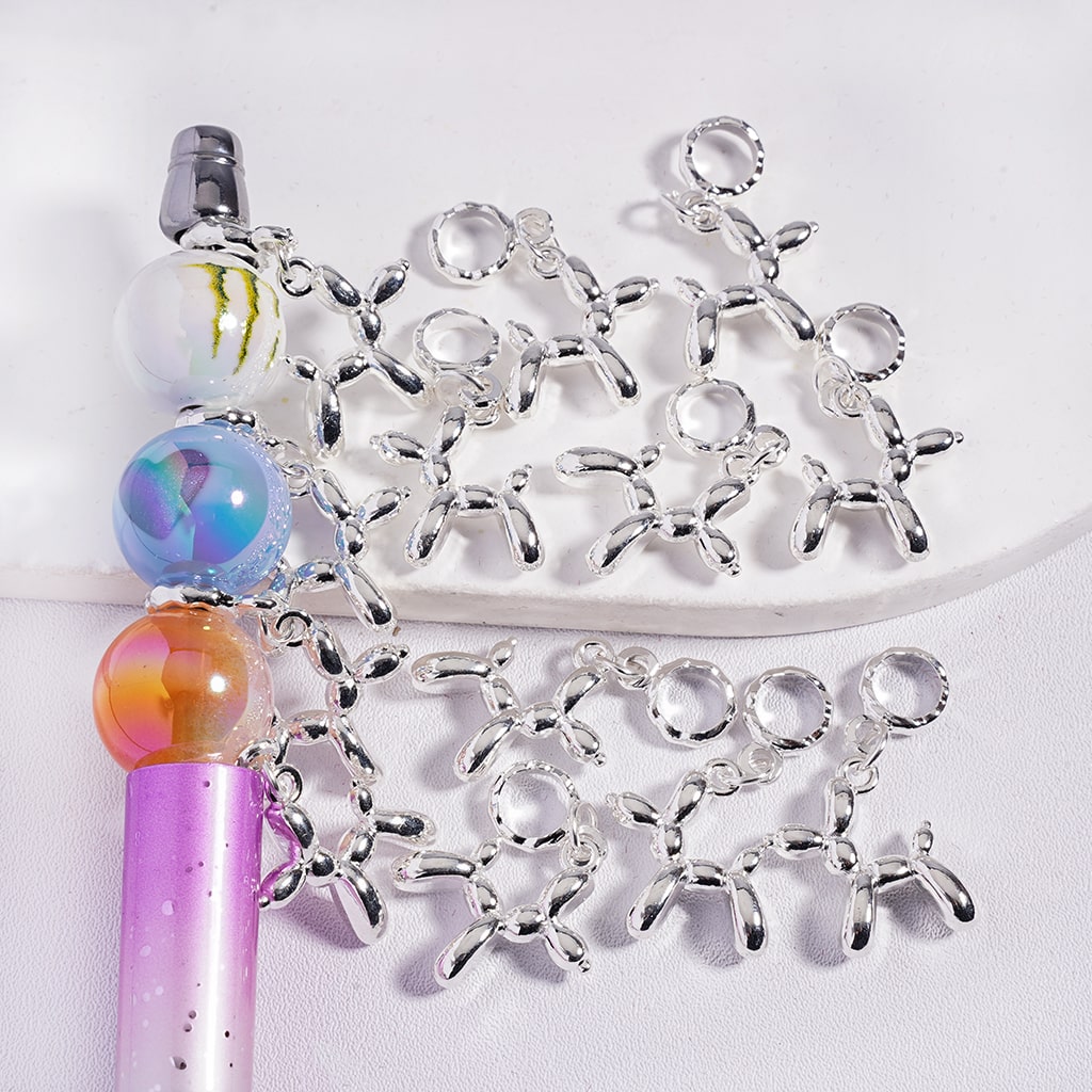 Silver butterfly charms on a white background with a colorful pen and beads.

