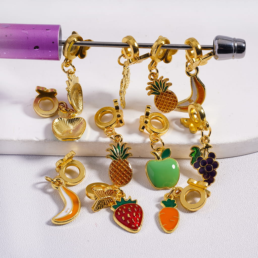 Gold charm bracelet with various fruit and vegetable charms on a white background