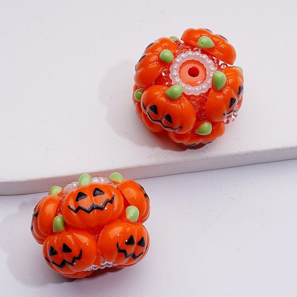 Two Halloween-themed pumpkin earrings on a white background

